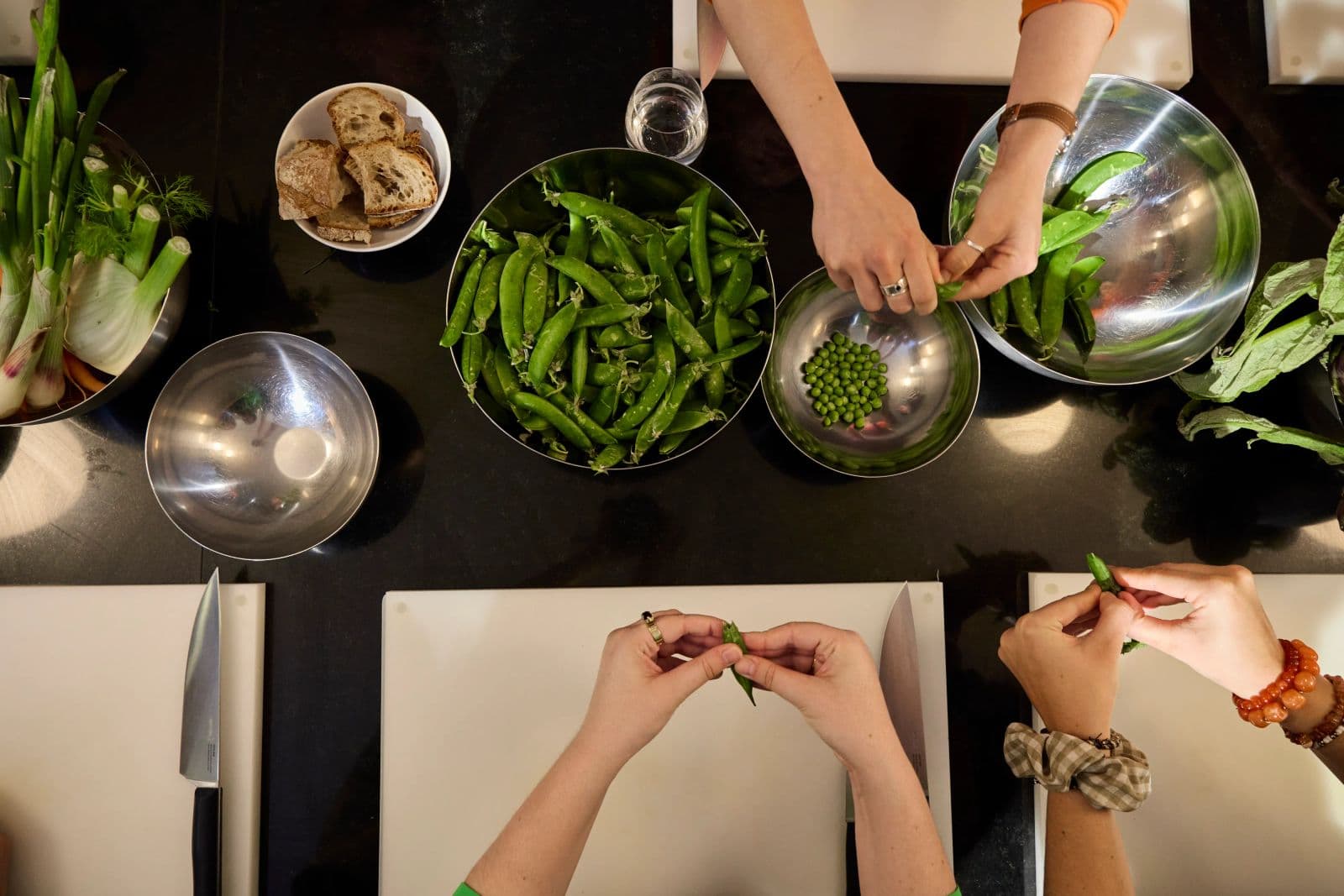 Overhead view of the worktop, several pairs of hands shelling peas, Paris 11