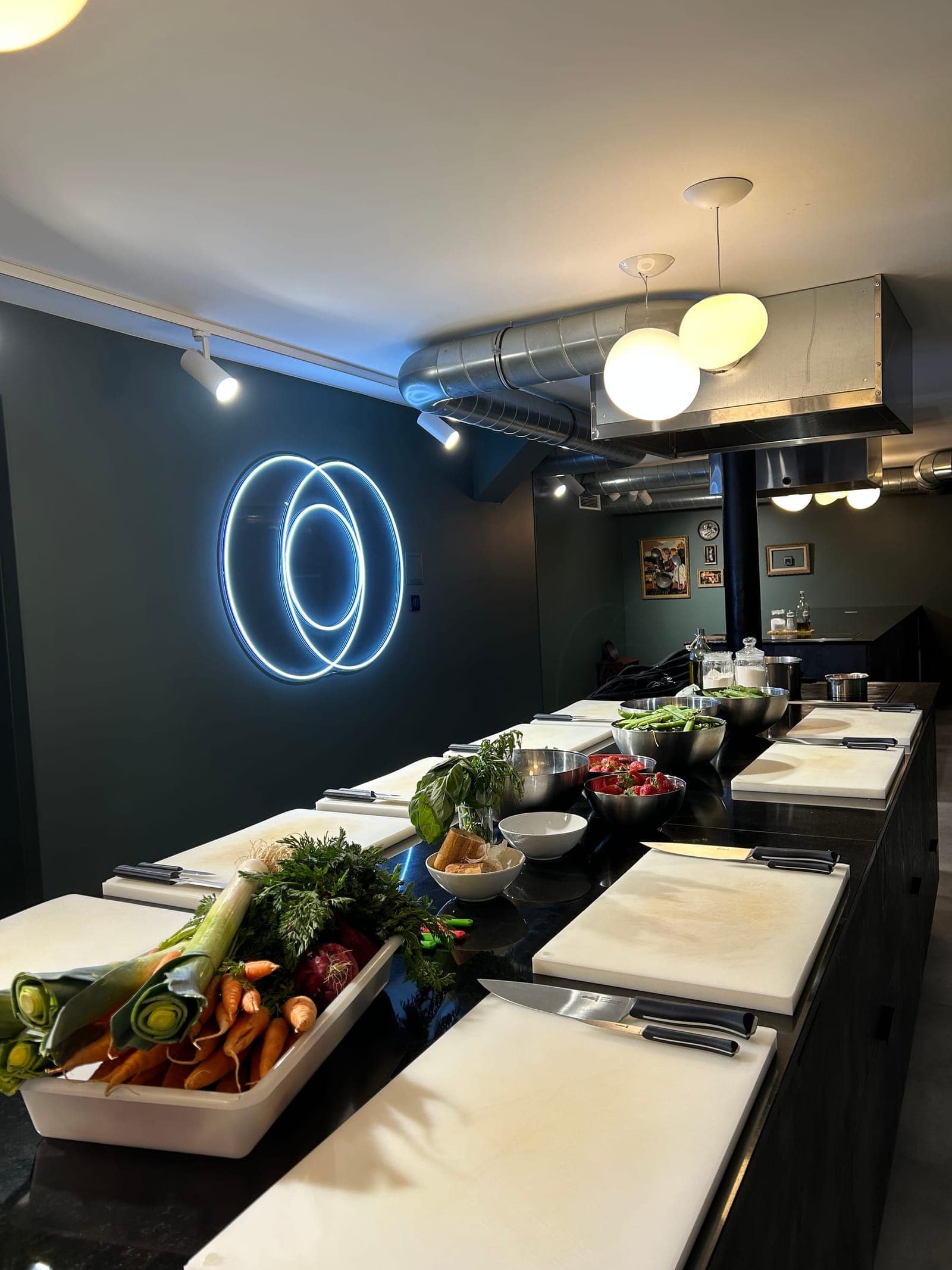 The kitchen of L'École du 3ème Cercle, workstations set under the neon logo, Paris 11