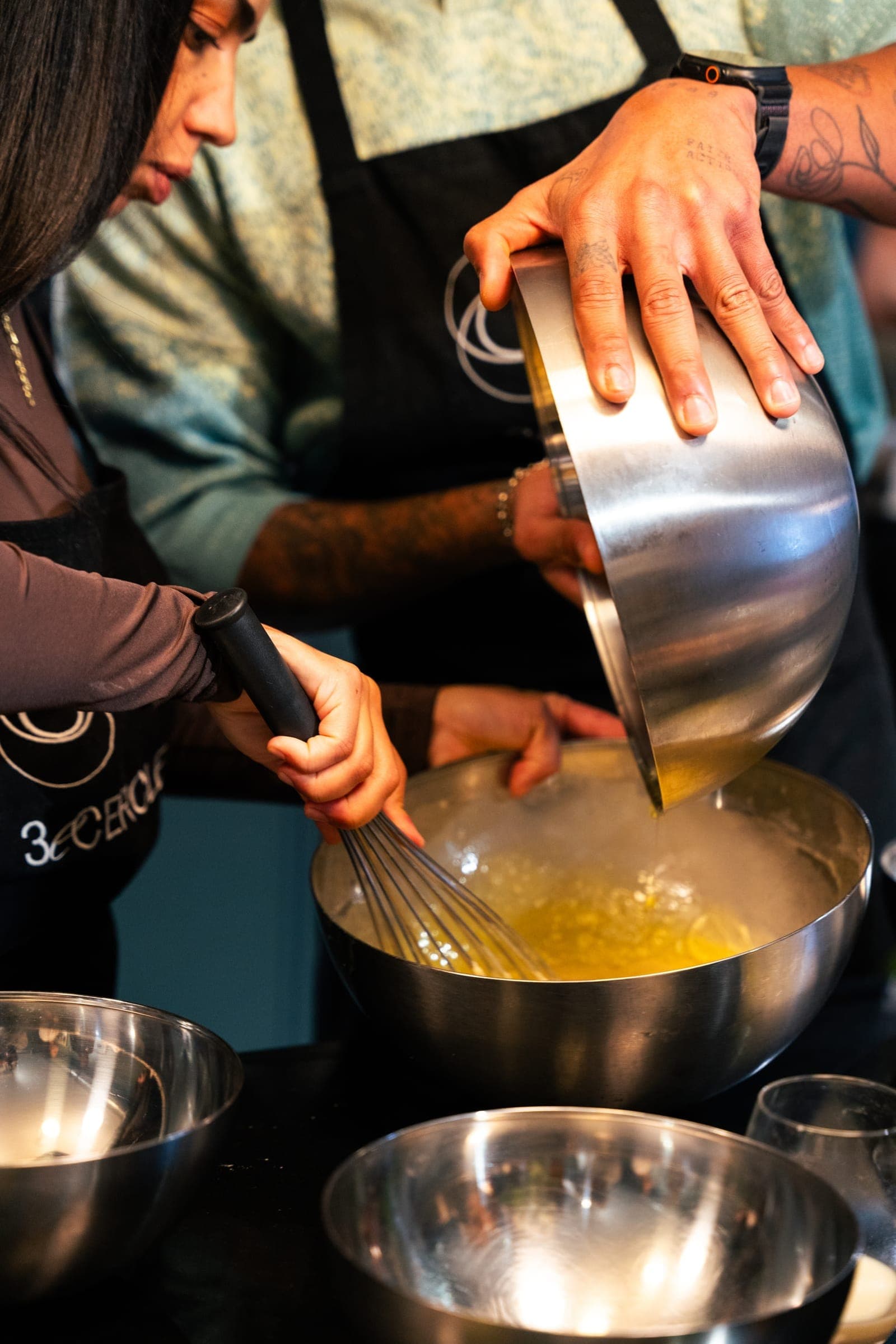 Le chef verse un appareil pendant que l'élève fouette, cours de pâtisserie, Paris 11