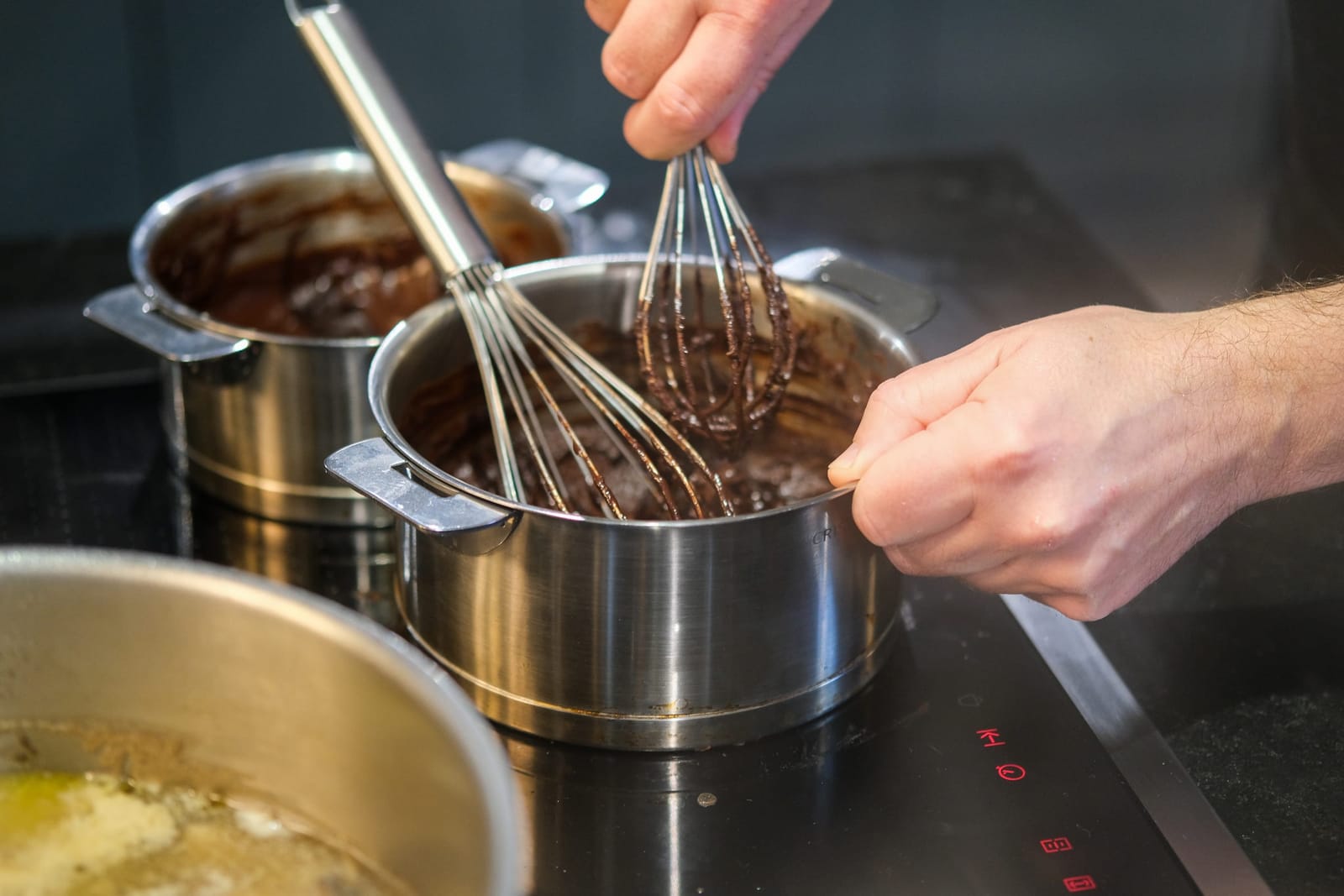 Whisks at work over pans of chocolate and cream, pastry class, Paris 11